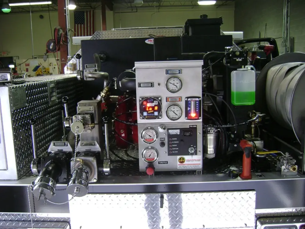 Exterior view of small fire truck showing cab, body compartments, and wheel/tire area.