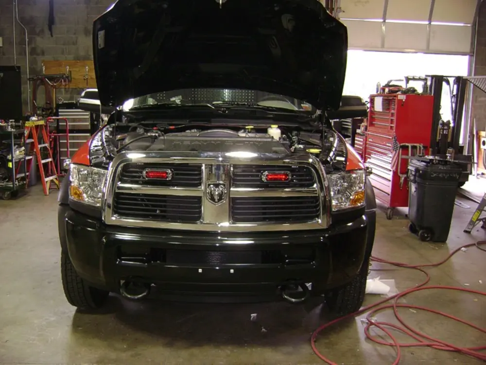Exterior view of small fire truck showing cab, body compartments, and wheel/tire area.