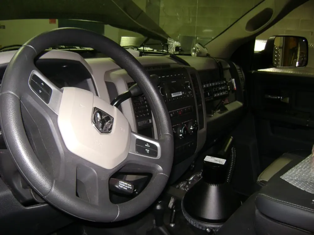 Exterior view of small fire truck showing cab, body compartments, and wheel/tire area.