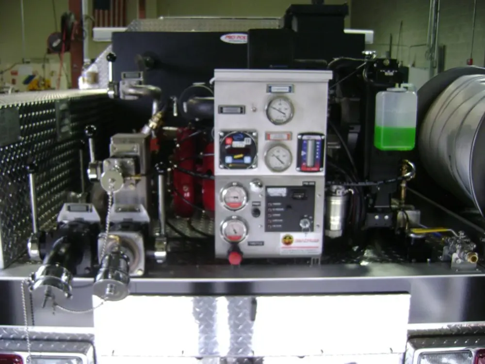 Exterior view of small fire truck showing cab, body compartments, and wheel/tire area.