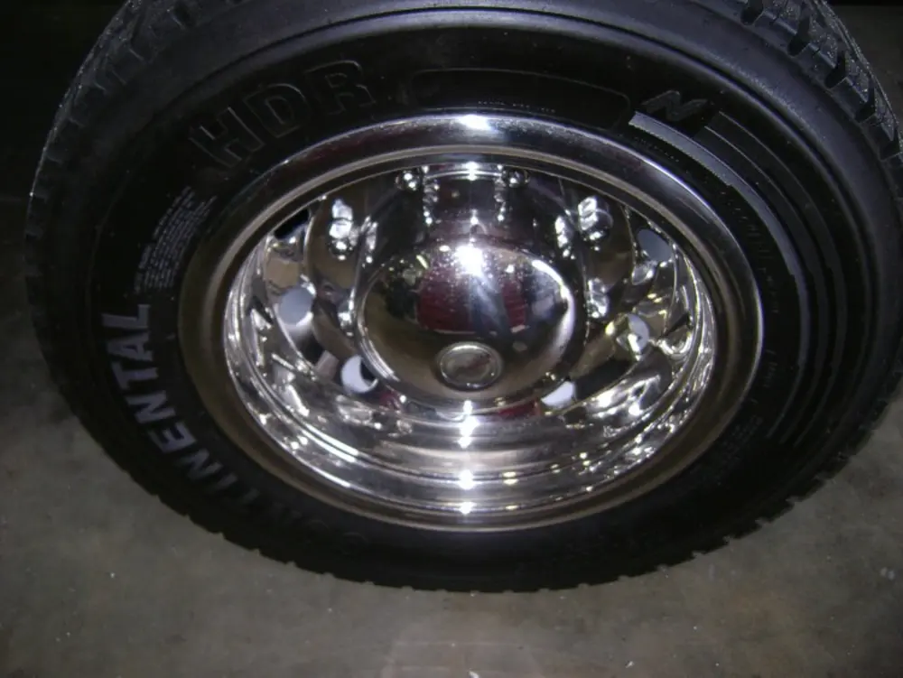 Exterior view of small fire truck showing cab, body compartments, and wheel/tire area.