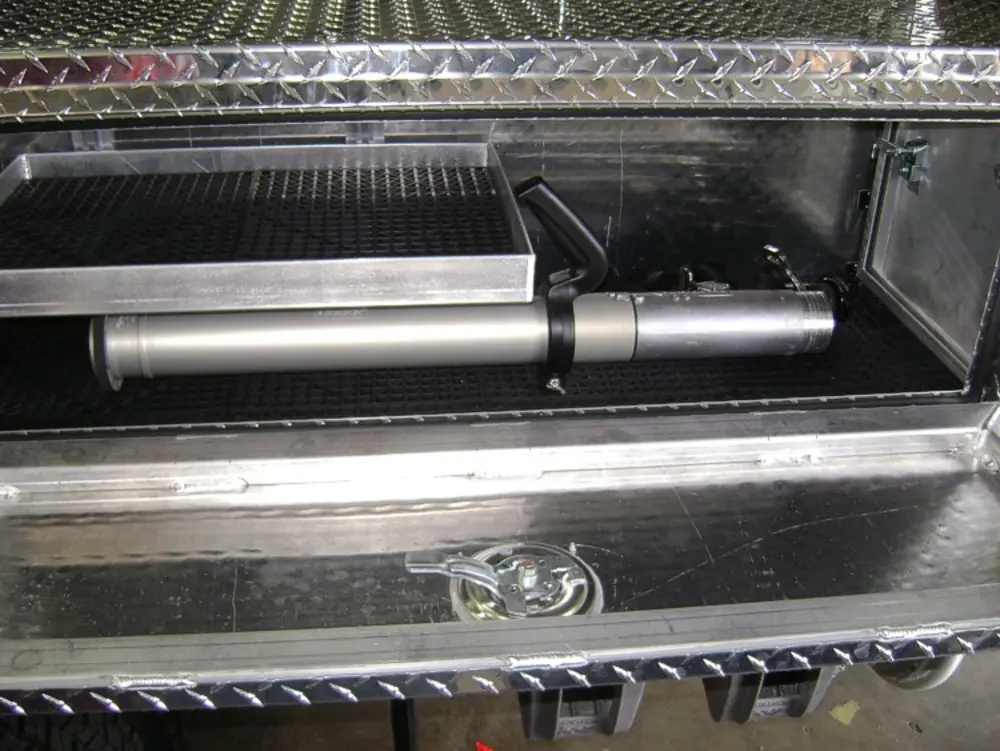 Exterior view of small fire truck showing cab, body compartments, and wheel/tire area.