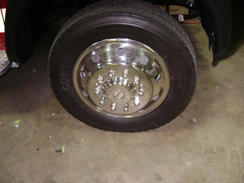 Exterior view of small fire truck showing cab, body compartments, and wheel/tire area.