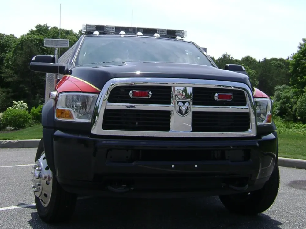 Exterior view of small fire truck showing cab, body compartments, and wheel/tire area.