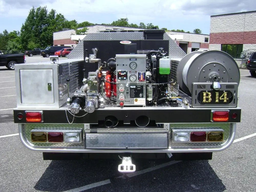 Exterior view of small fire truck showing cab, body compartments, and wheel/tire area.