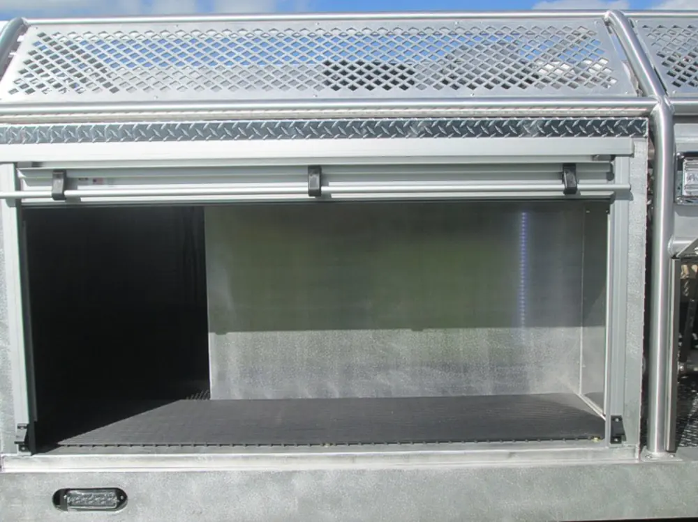 Exterior view of small fire truck showing cab, body compartments, and wheel/tire area.