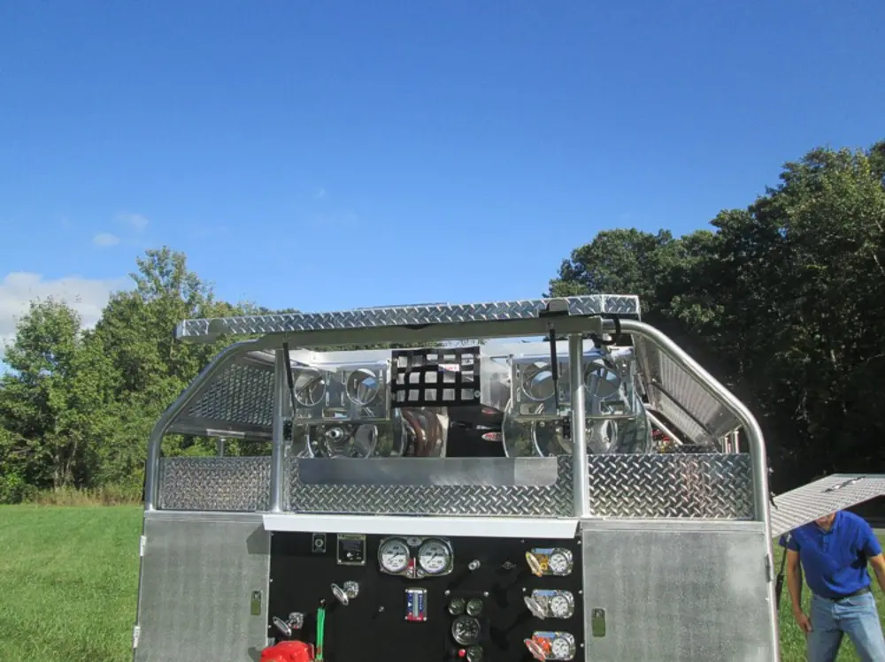 Exterior view of small fire truck showing cab, body compartments, and wheel/tire area.