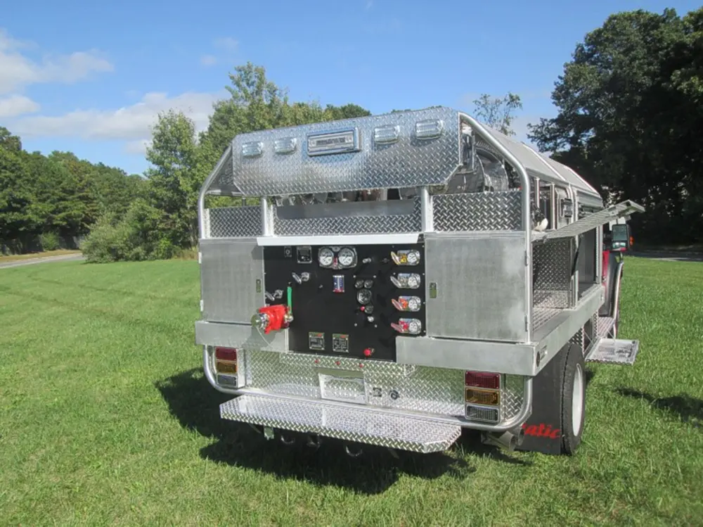 Exterior view of small fire truck showing cab, body compartments, and wheel/tire area.