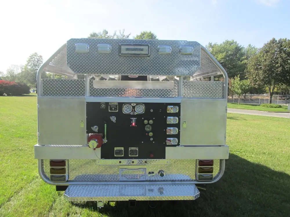 Exterior view of small fire truck showing cab, body compartments, and wheel/tire area.