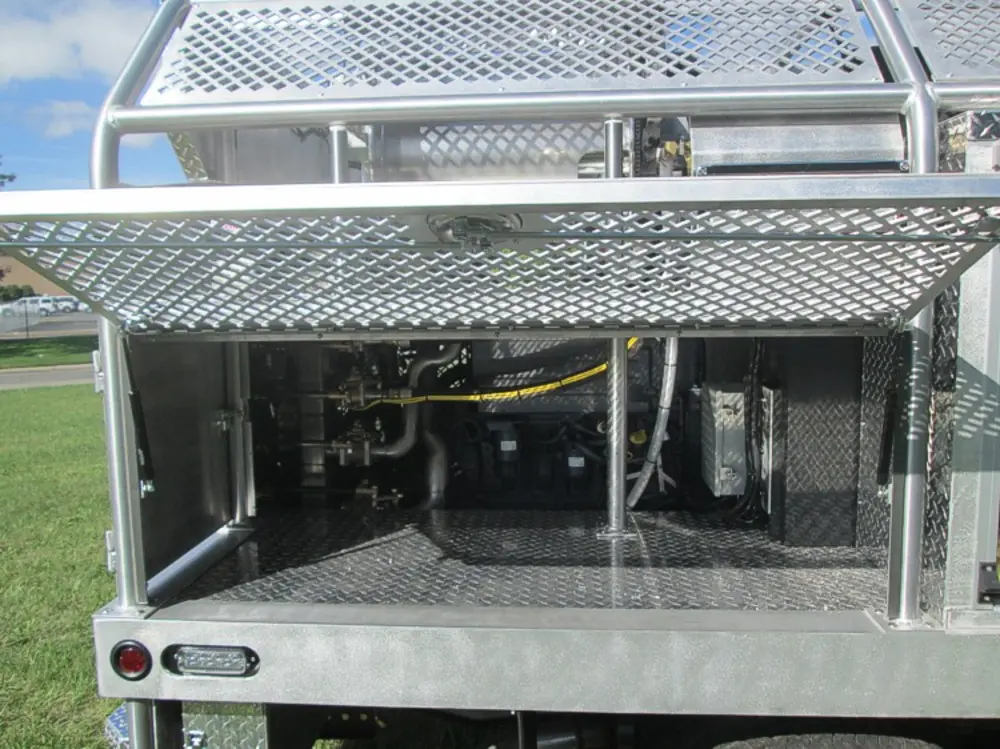 Exterior view of small fire truck showing cab, body compartments, and wheel/tire area.