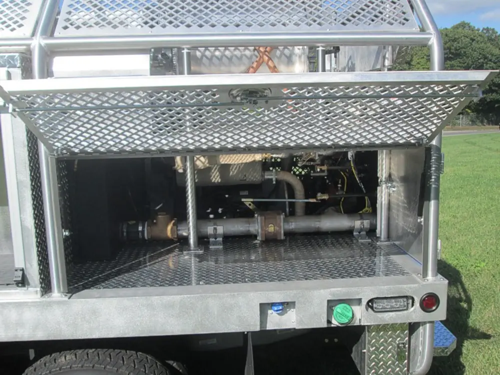 Exterior view of small fire truck showing cab, body compartments, and wheel/tire area.