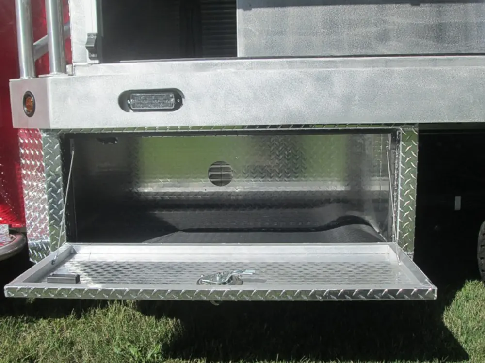 Exterior view of small fire truck showing cab, body compartments, and wheel/tire area.