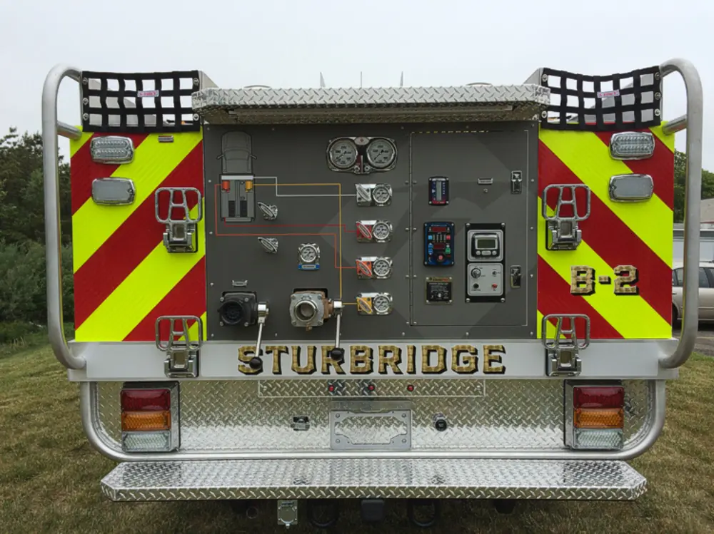 Exterior view of small fire truck showing cab, body compartments, and wheel/tire area.
