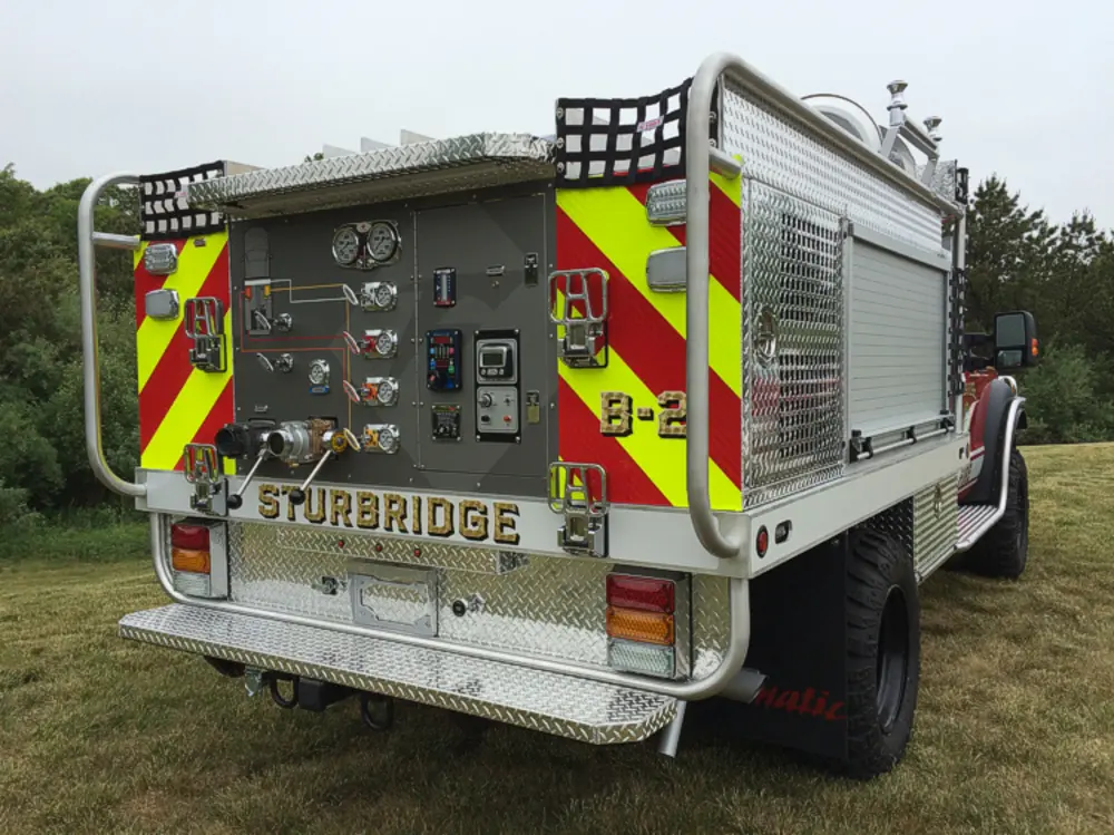 Exterior view of small fire truck showing cab, body compartments, and wheel/tire area.
