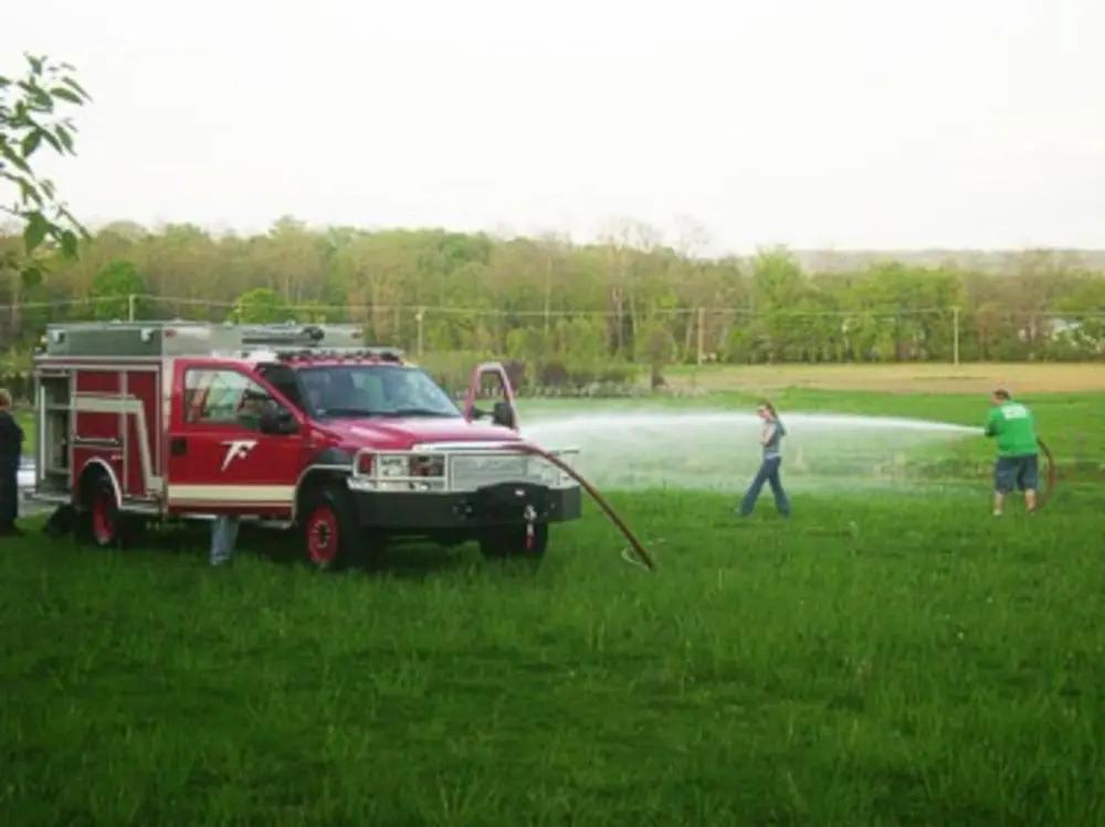 Exterior view of small fire truck showing cab, body compartments, and wheel/tire area.