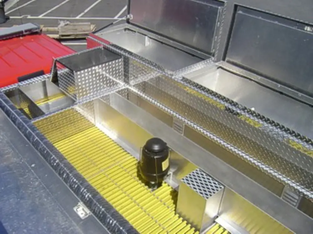 Exterior view of small fire truck showing cab, body compartments, and wheel/tire area.