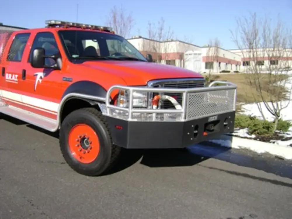 Exterior view of small fire truck showing cab, body compartments, and wheel/tire area.
