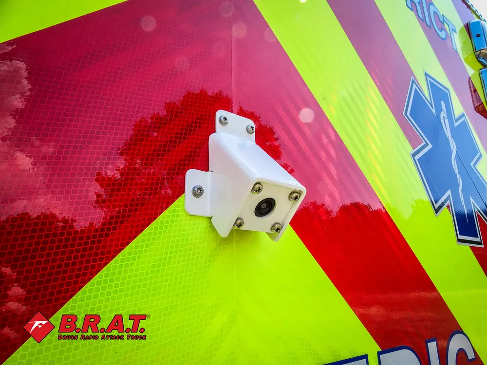 Exterior view of small fire truck showing cab, body compartments, and wheel/tire area.