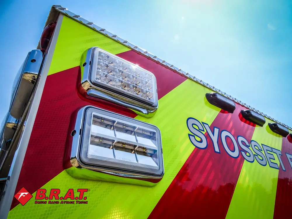 Exterior view of small fire truck showing cab, body compartments, and wheel/tire area.