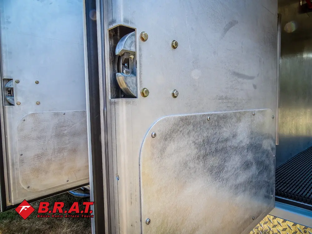 Exterior view of small fire truck showing cab, body compartments, and wheel/tire area.