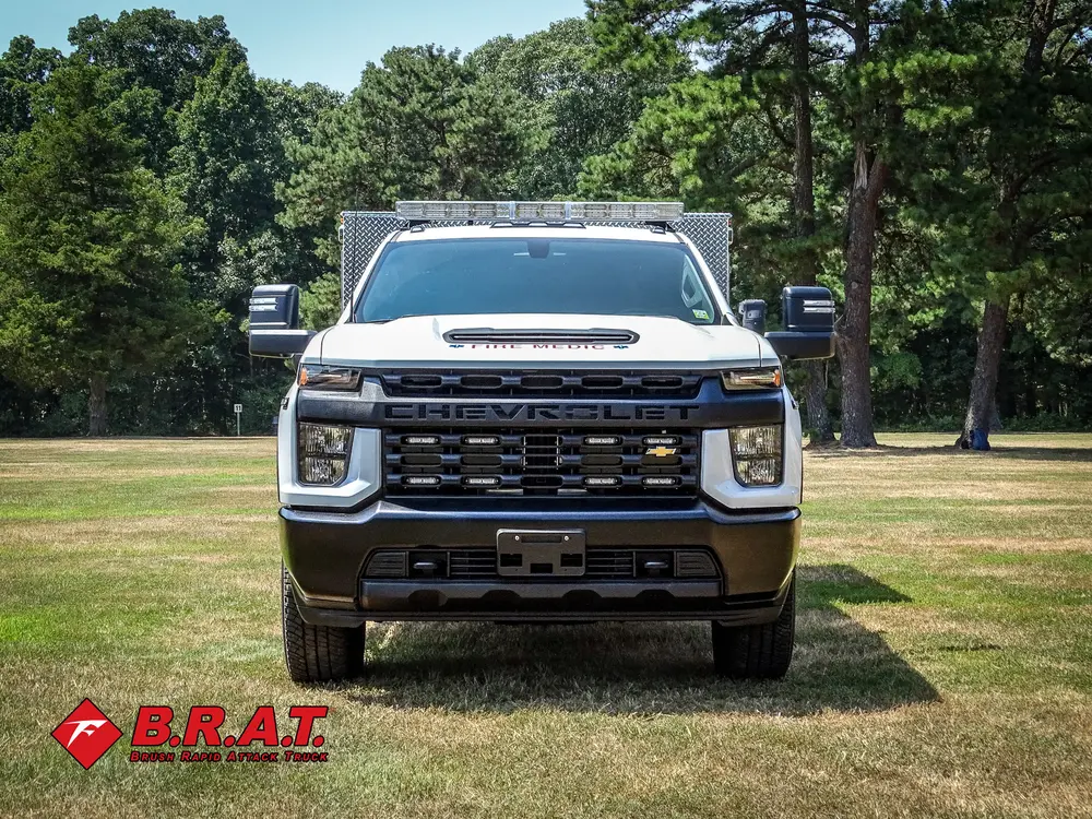 Exterior view of small fire truck showing cab, body compartments, and wheel/tire area.