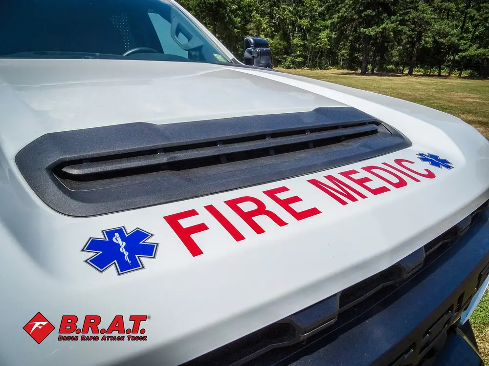 Exterior view of small fire truck showing cab, body compartments, and wheel/tire area.