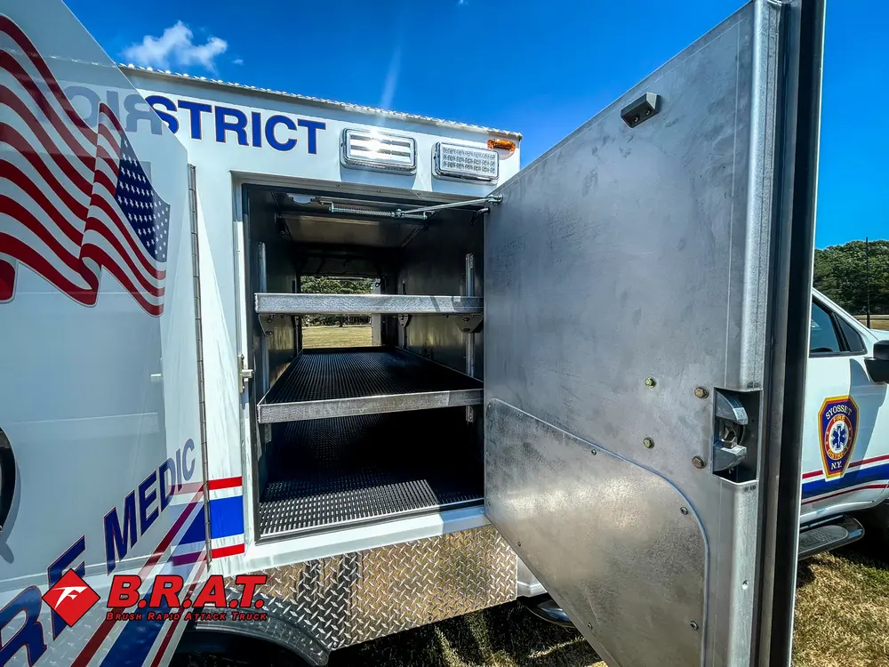 Exterior view of small fire truck showing cab, body compartments, and wheel/tire area.