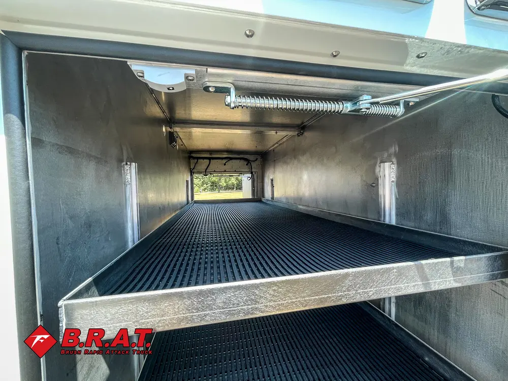 Exterior view of small fire truck showing cab, body compartments, and wheel/tire area.