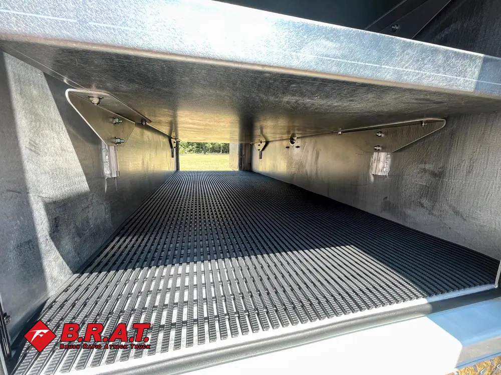 Exterior view of small fire truck showing cab, body compartments, and wheel/tire area.