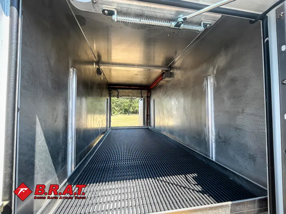 Exterior view of small fire truck showing cab, body compartments, and wheel/tire area.