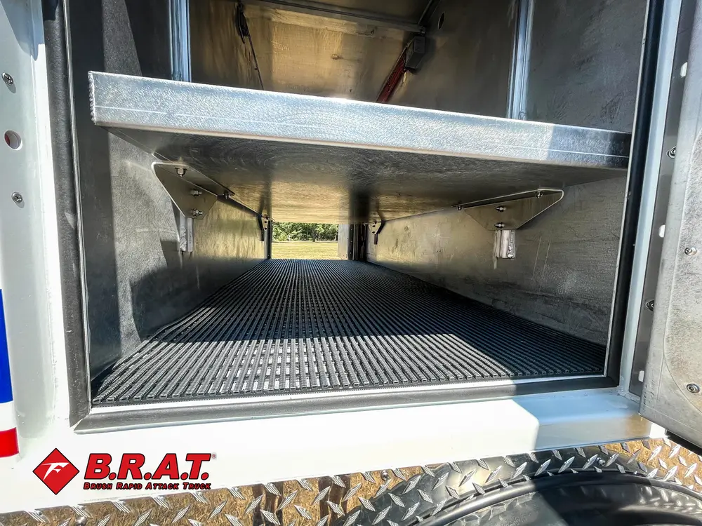 Exterior view of small fire truck showing cab, body compartments, and wheel/tire area.