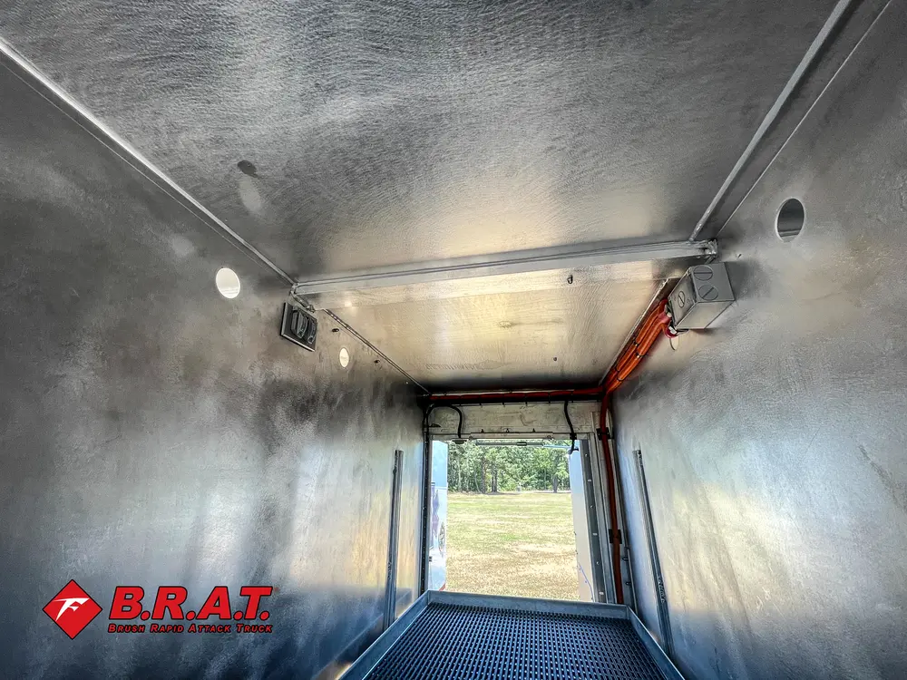 Exterior view of small fire truck showing cab, body compartments, and wheel/tire area.