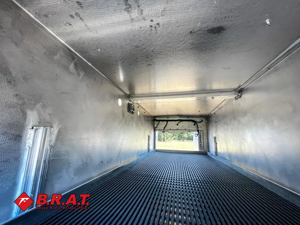 Exterior view of small fire truck showing cab, body compartments, and wheel/tire area.