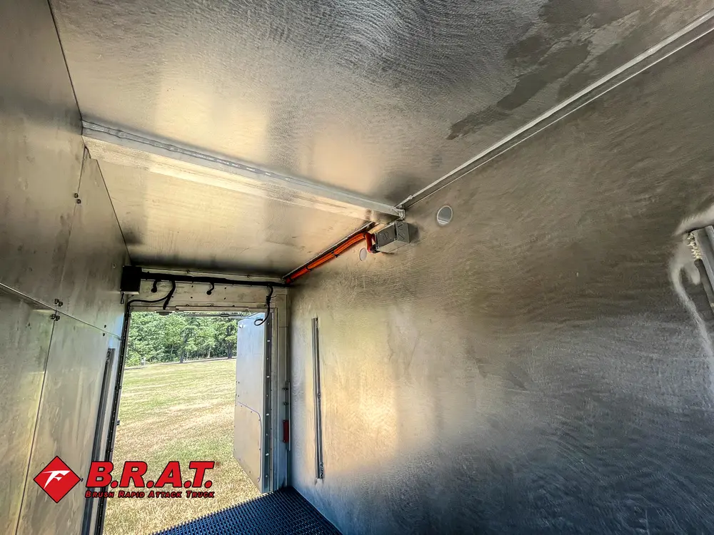 Exterior view of small fire truck showing cab, body compartments, and wheel/tire area.