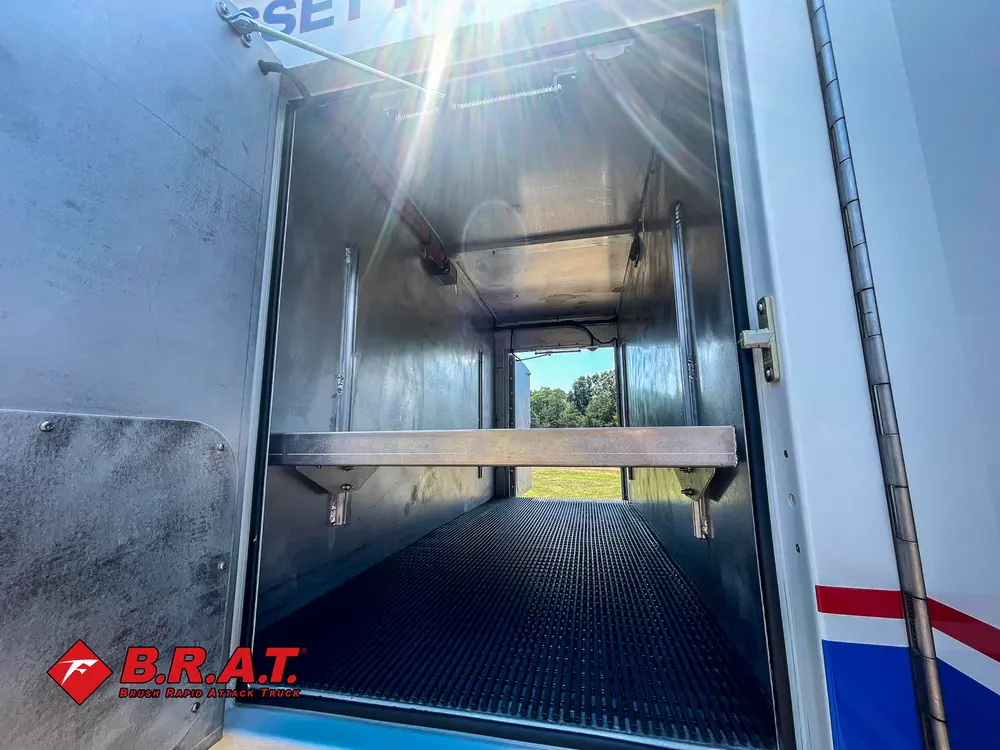 Exterior view of small fire truck showing cab, body compartments, and wheel/tire area.