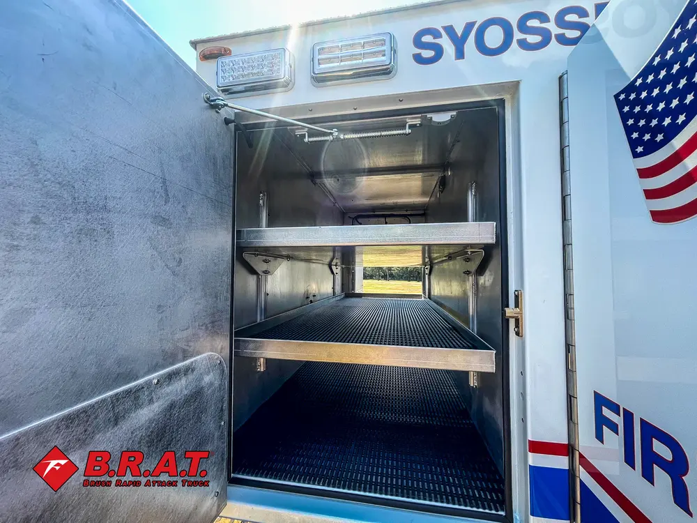 Exterior view of small fire truck showing cab, body compartments, and wheel/tire area.