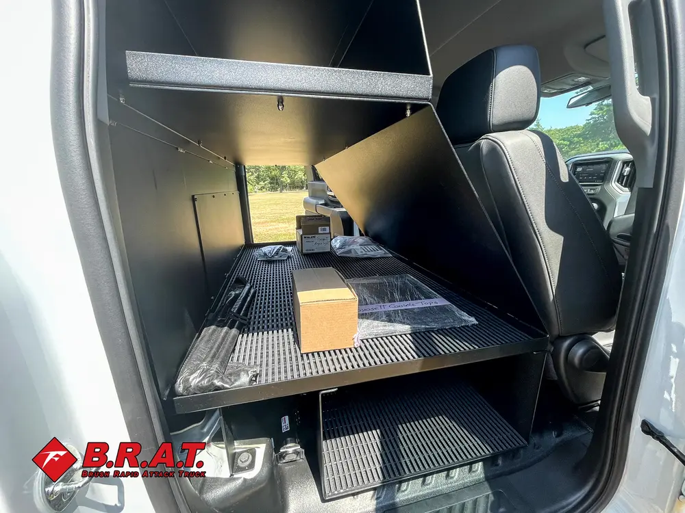 Exterior view of small fire truck showing cab, body compartments, and wheel/tire area.