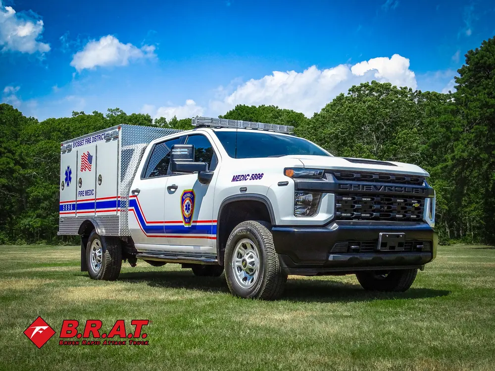 Exterior view of small fire truck showing cab, body compartments, and wheel/tire area.