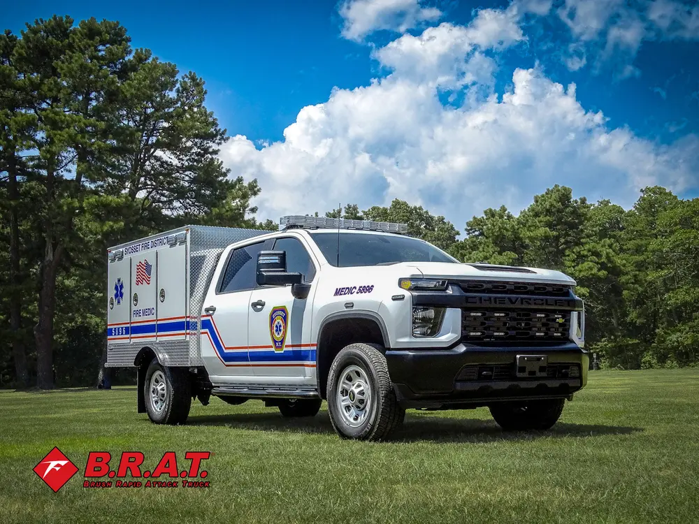 Exterior view of small fire truck showing cab, body compartments, and wheel/tire area.