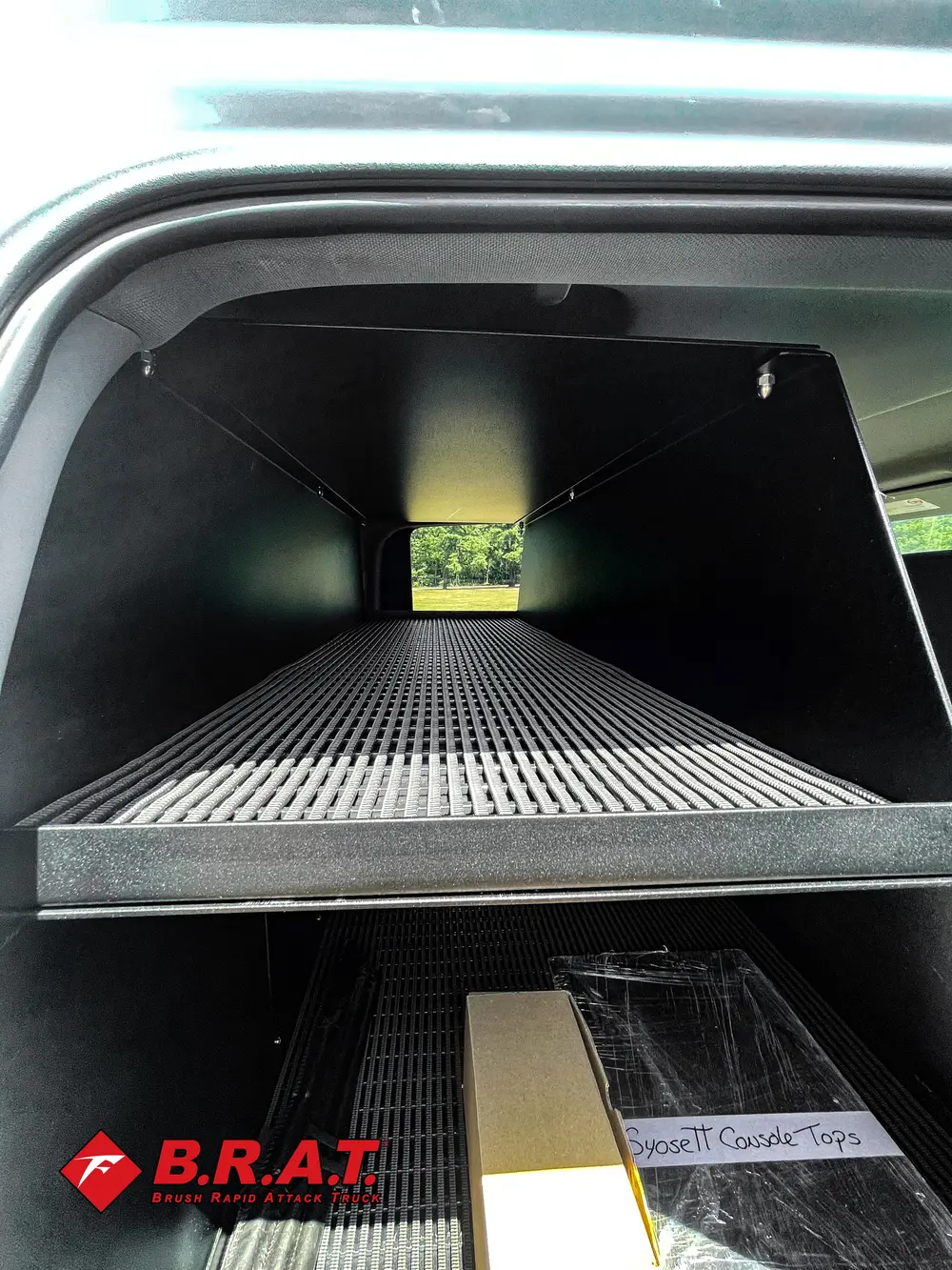 Exterior view of small fire truck showing cab, body compartments, and wheel/tire area.