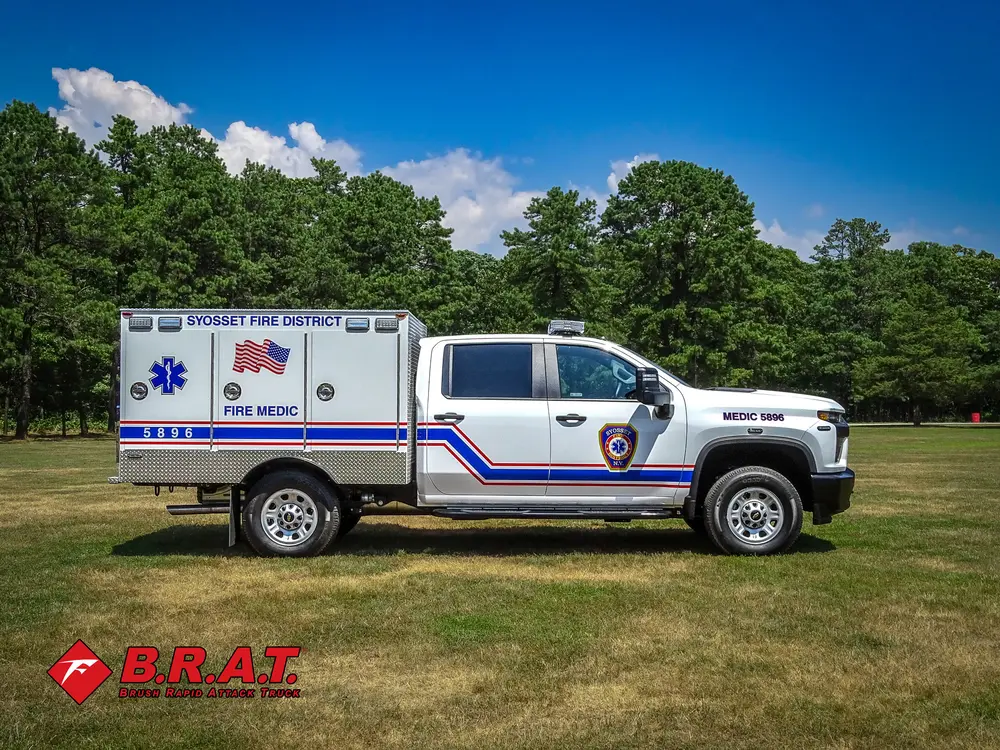 Exterior view of small fire truck showing cab, body compartments, and wheel/tire area.