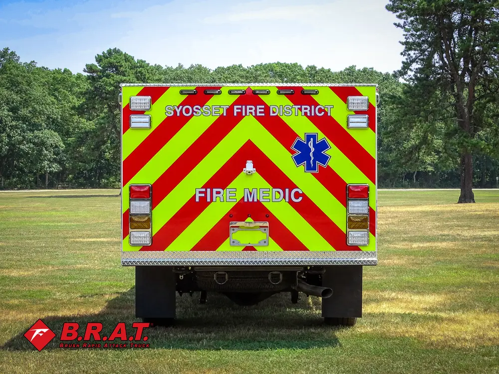 Exterior view of small fire truck showing cab, body compartments, and wheel/tire area.