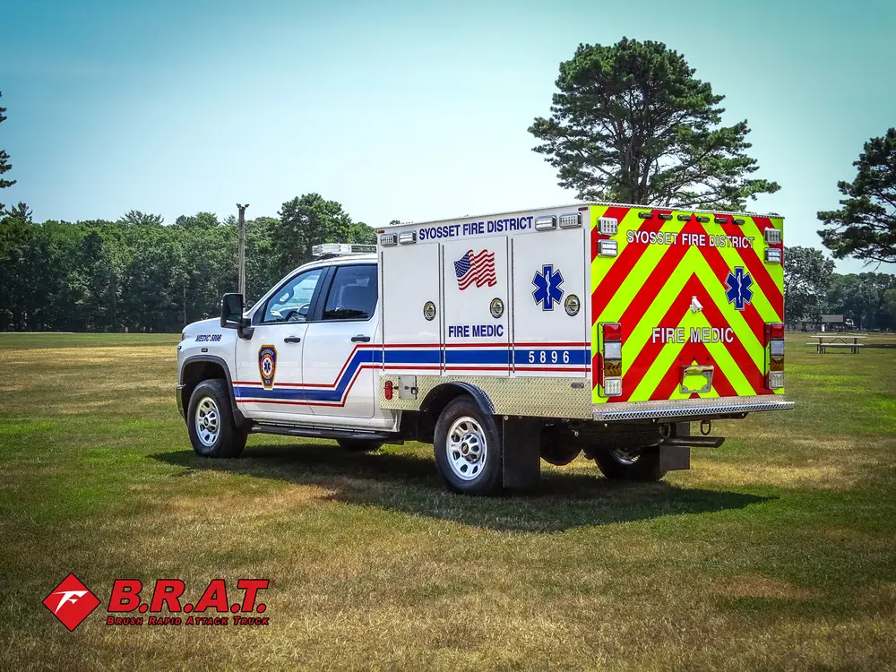 Exterior view of small fire truck showing cab, body compartments, and wheel/tire area.