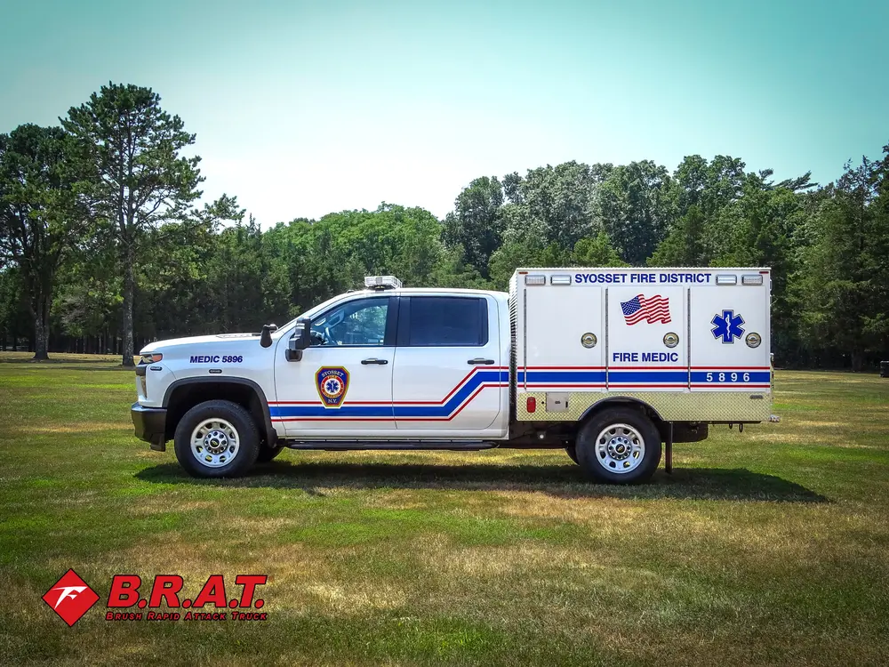 Exterior view of small fire truck showing cab, body compartments, and wheel/tire area.
