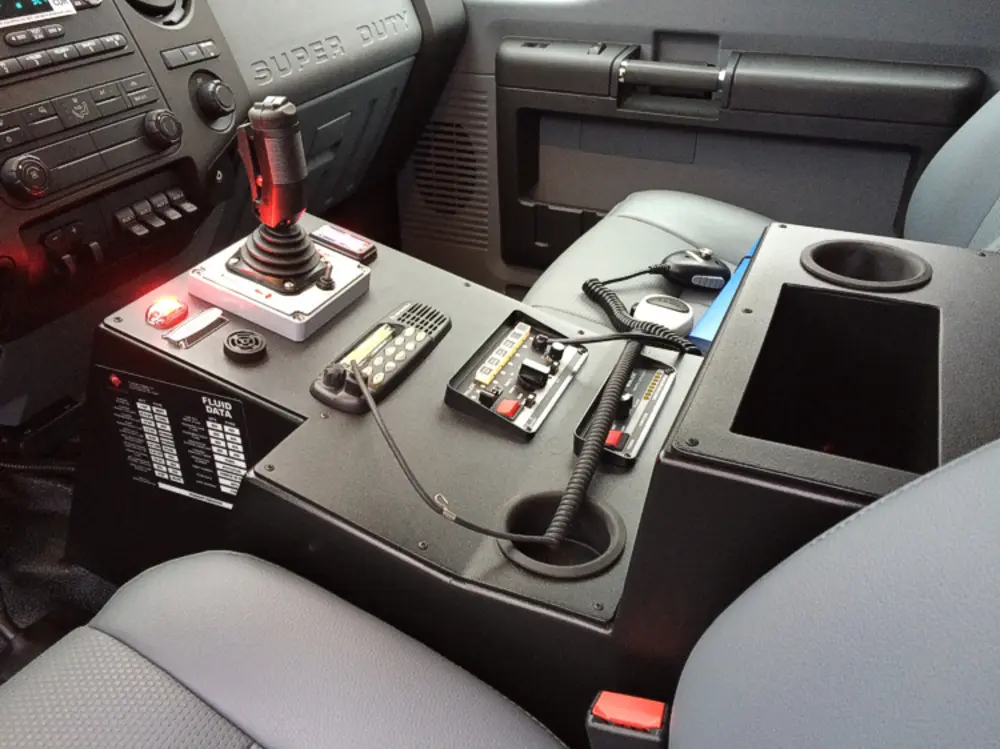 Exterior view of small fire truck showing cab, body compartments, and wheel/tire area.