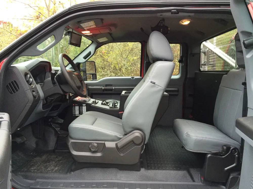 Exterior view of small fire truck showing cab, body compartments, and wheel/tire area.