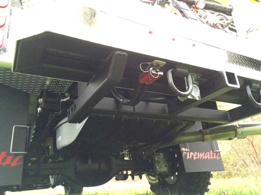 Exterior view of small fire truck showing cab, body compartments, and wheel/tire area.