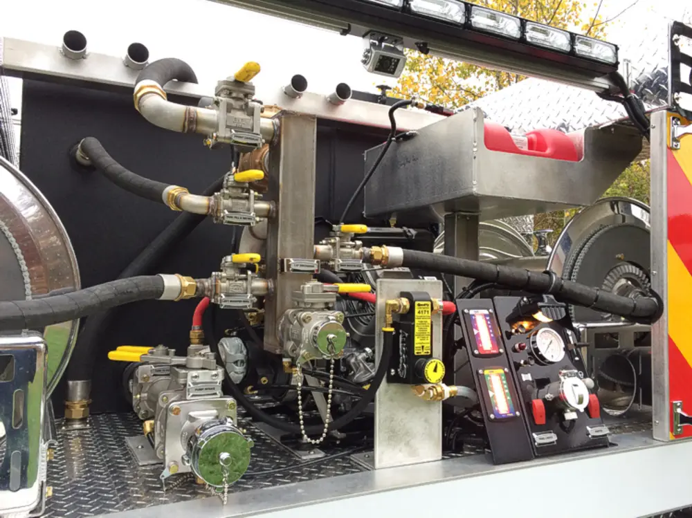 Exterior view of small fire truck showing cab, body compartments, and wheel/tire area.