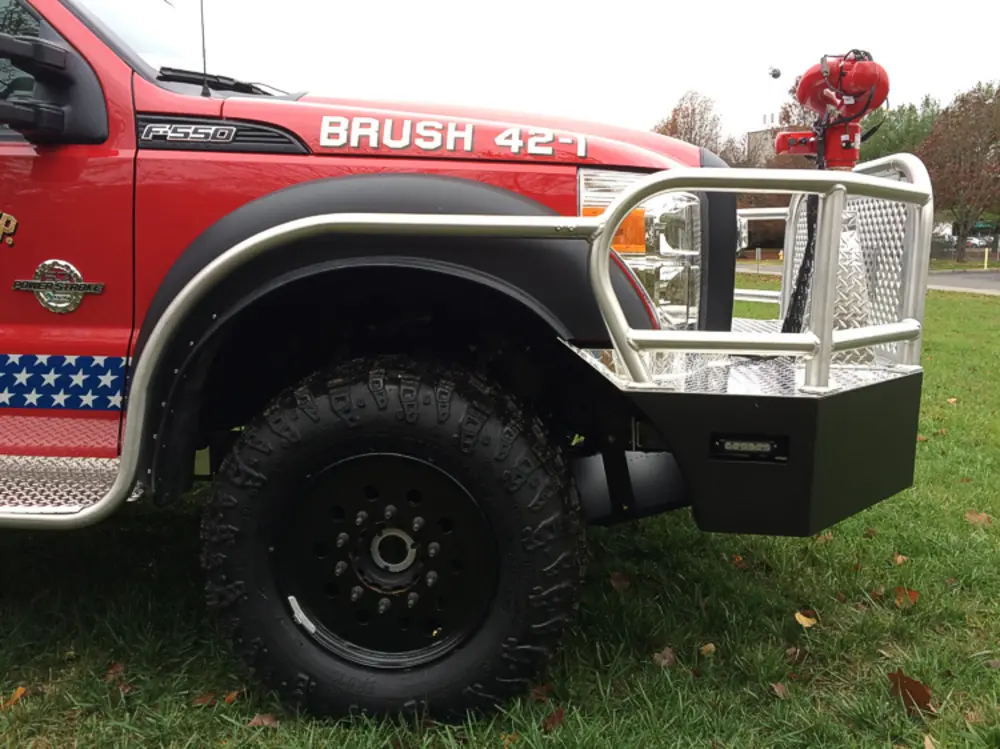 Exterior view of small fire truck showing cab, body compartments, and wheel/tire area.