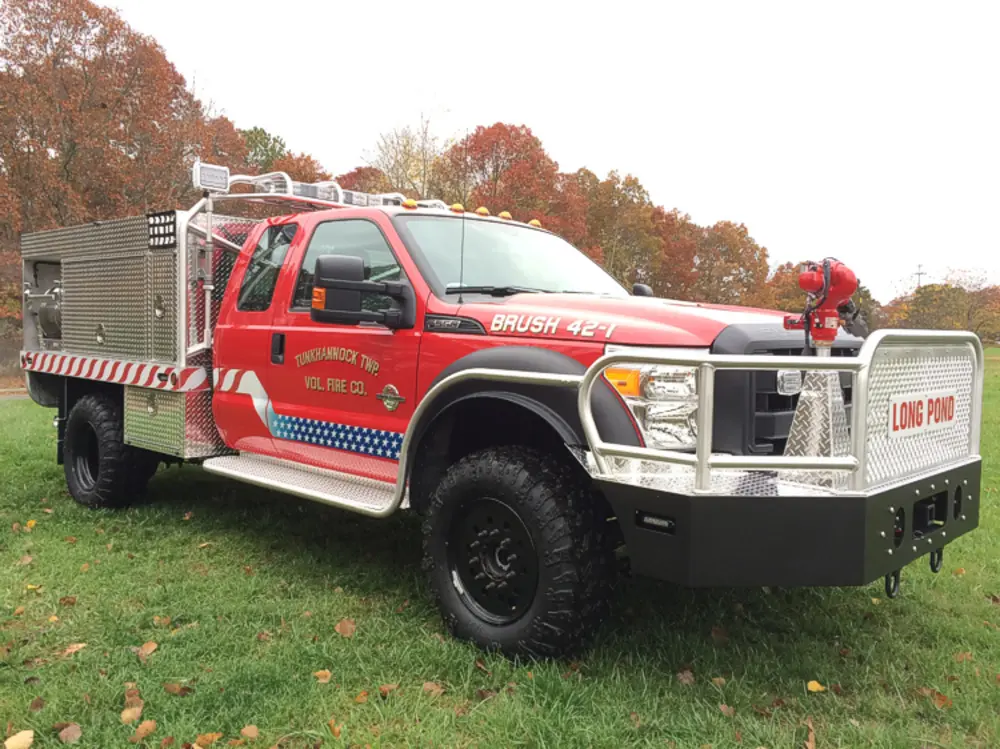 Exterior view of small fire truck showing cab, body compartments, and wheel/tire area.